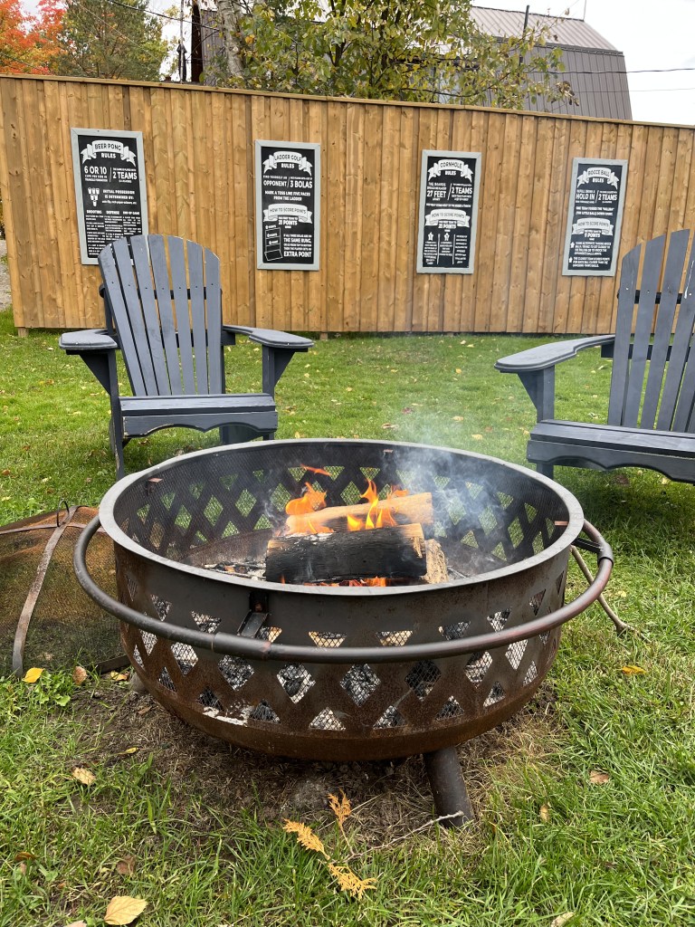 Blue muskoka chairs around a fire pit in Cottage Country during a fall weekend getaway in Ontario to view the Fall leaves.
